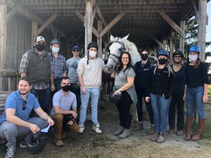 Group of people in barn with horse