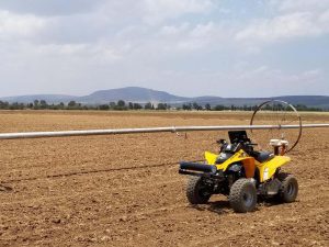 ATV in field beside pivots with mountainous background
